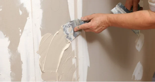 Service professional performing drywall repair in residential home.